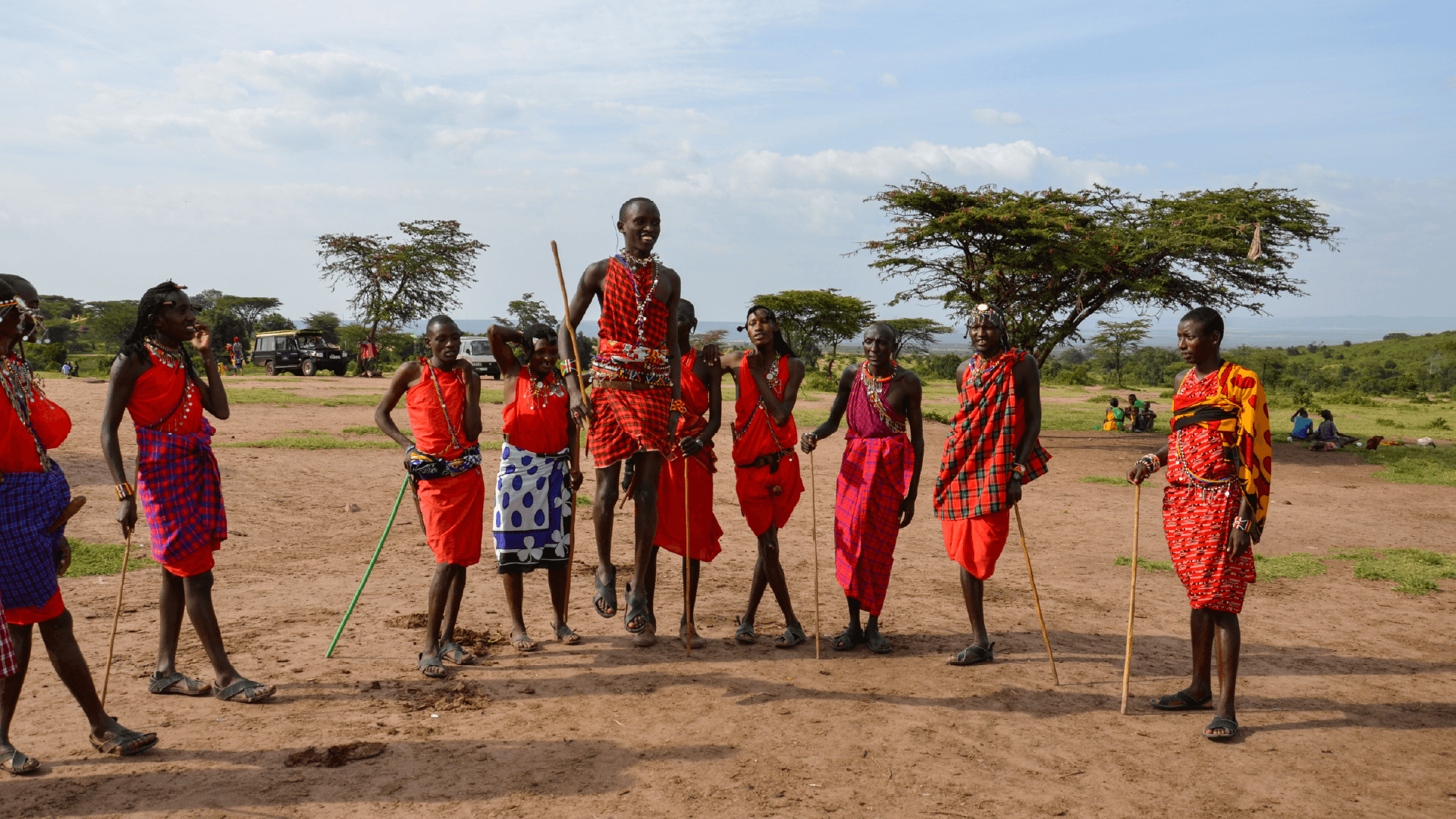 Members of a Maasai tribe in Kenya forming a circle with one member partaking in the jumping tradition known as Adumu, captured by Annelieke Huijgens