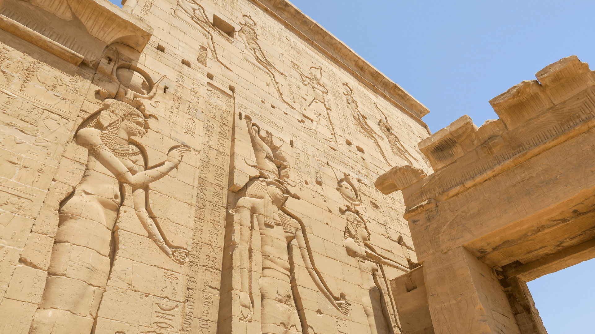 Travellers walking through the intricately carved columns of Philae Temple in Aswan, Egypt captured by Amie Bunnik