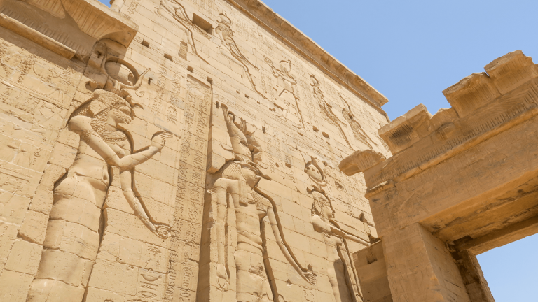 Travellers walking through the intricately carved columns of Philae Temple in Aswan, Egypt captured by Amie Bunnik