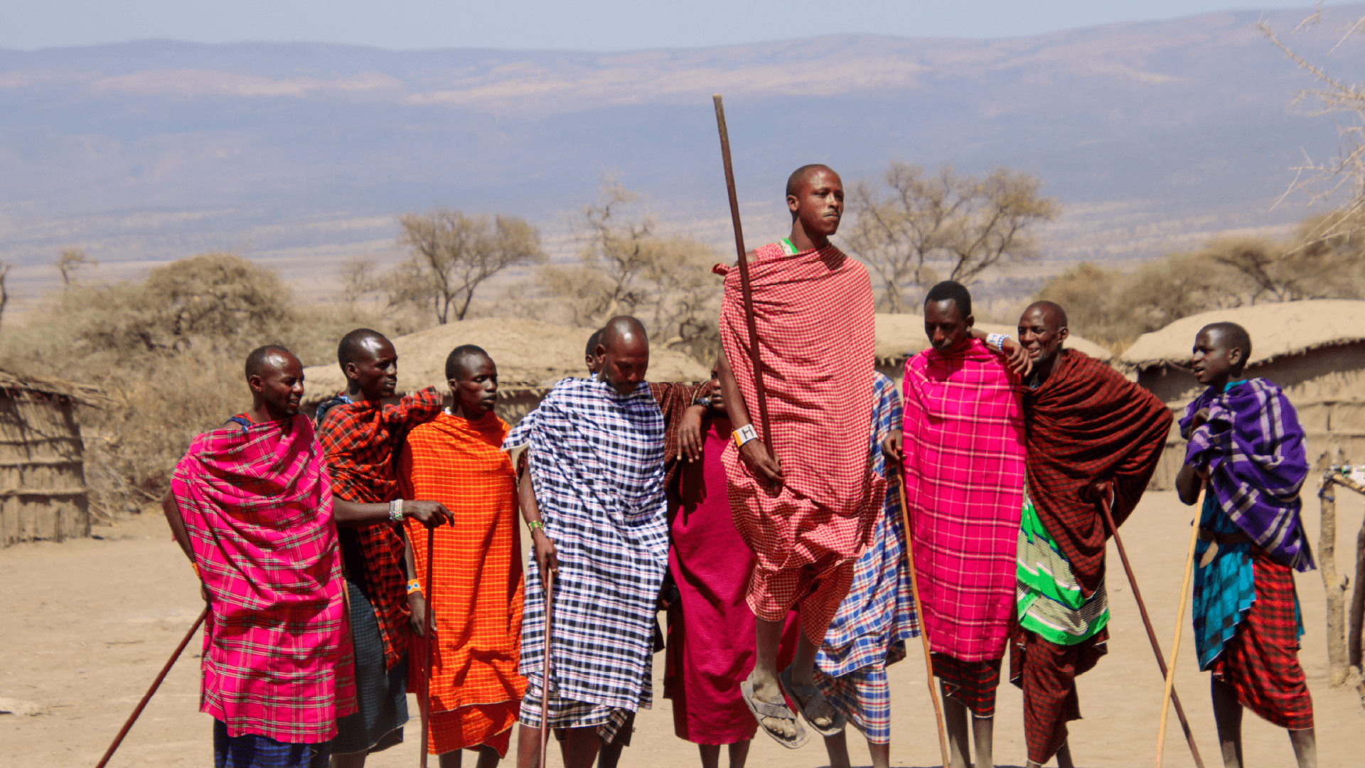 Members of a Maasai Village in colourful, patterned dress in Tanzania performing a traditional Maasai jumping ceremony captured by Annelieke Huijgens