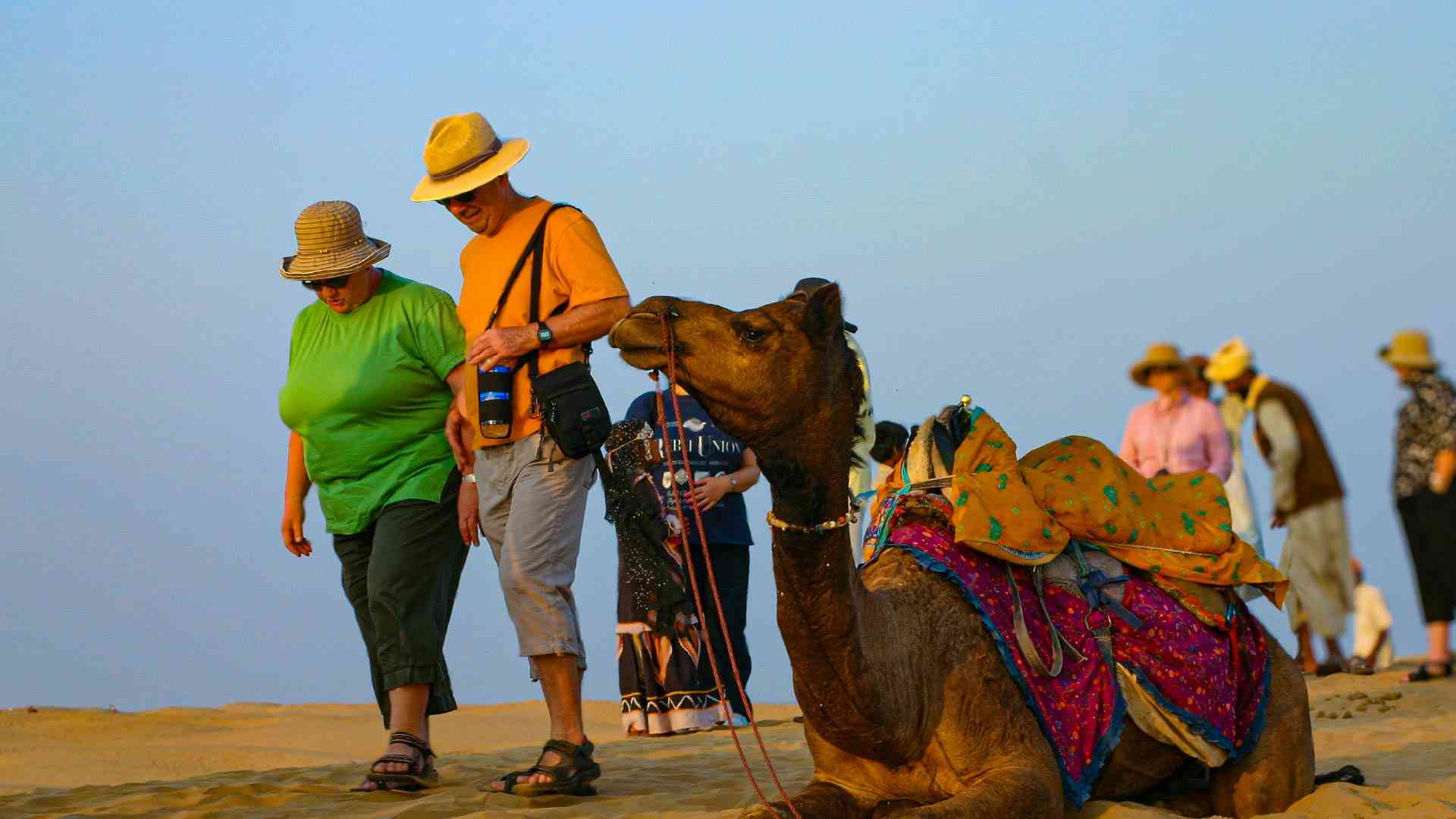 Two people next to a camel in the Thar Desert, India