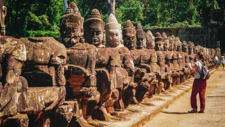 Woman looking at statues in Angkor Wat on a Cambodia tour