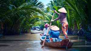 Locals in a traditional boat in the Mekong Delta on a Vietnam tour