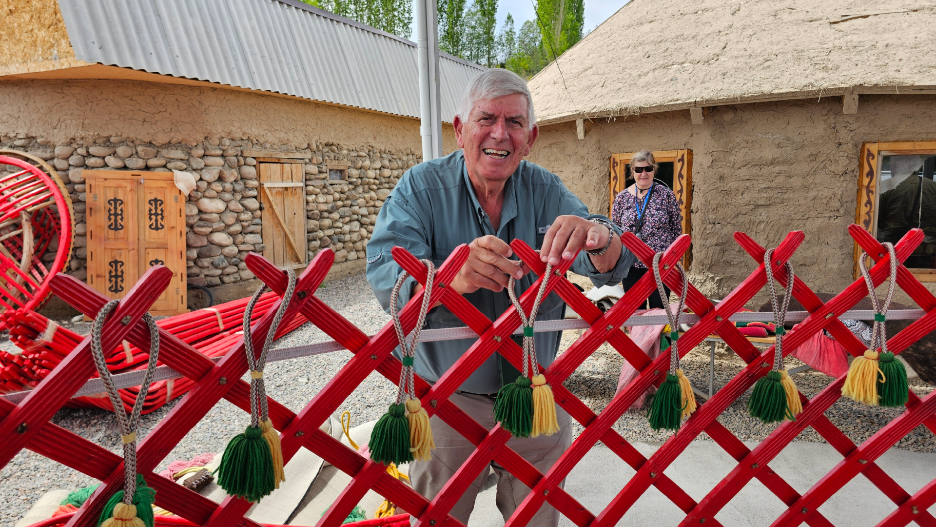 A happy Bunnik Tours traveller tying a tassel on a yurt during a yurt building workshop in Kyrgyzstan captured by Dennis Bunnik