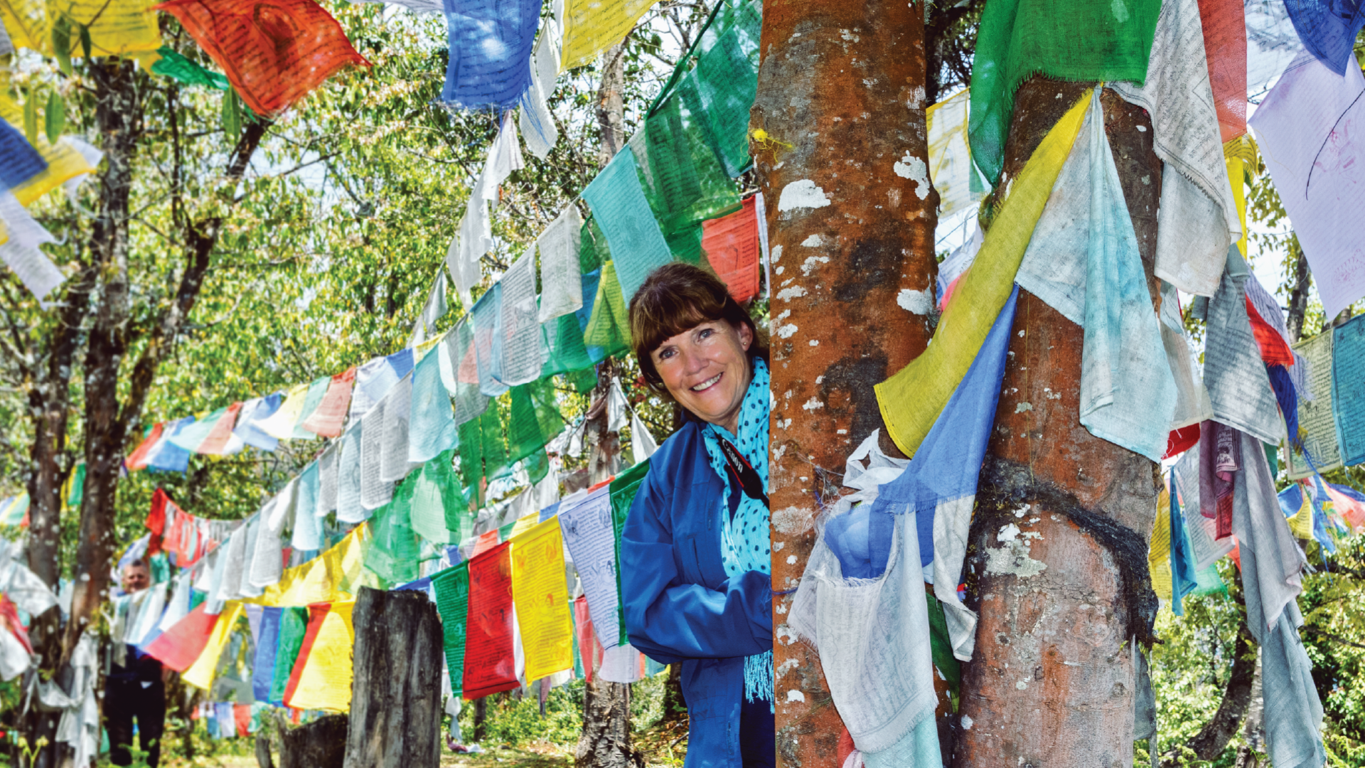 A person in between colourful prayer flags on a Bunnik Tour of Bhutan