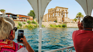 People looking at Philae Temple from the Nile River in Aswan, Egypt by Dennis Bunnik