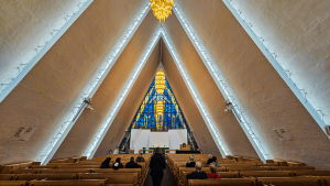 The peaked interior featuring a stained glass window at the end of the room of the Artic Cathedral, Tromsø, Norway, captured by Dennis Bunnik