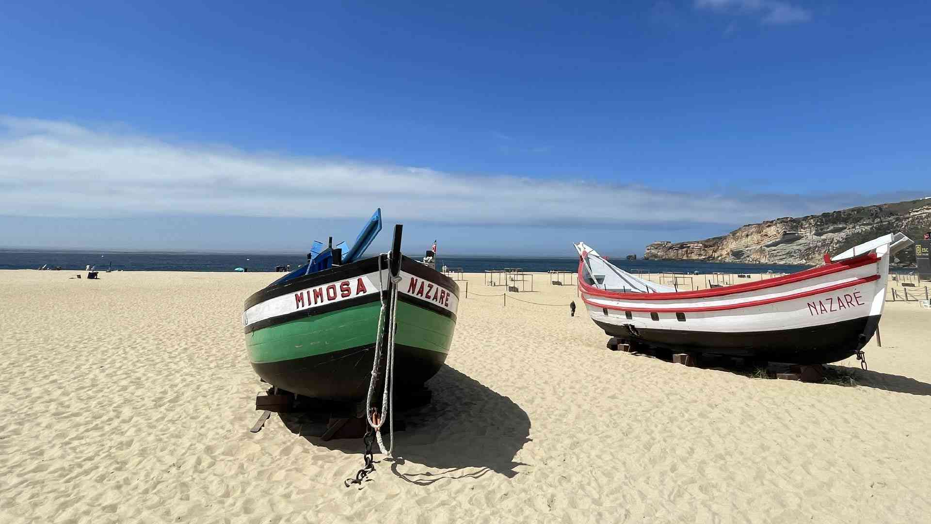 Colourful boats on white sand in Nazare, Portugal