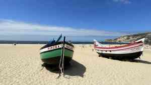 Colourful boats on white sand in Nazare, Portugal