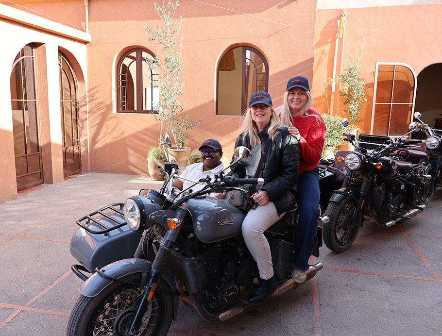 Two people sitting on a motorbike, with another in the sidecar