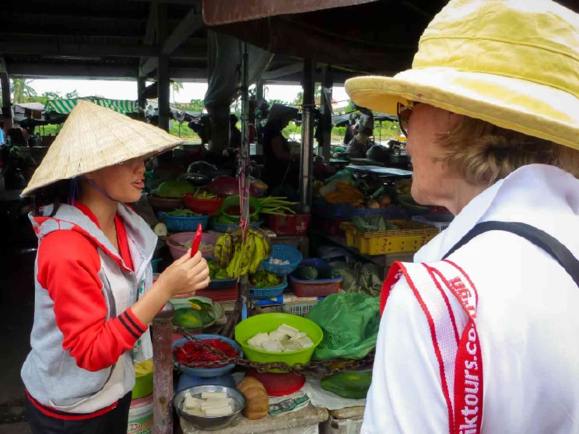 A local women showing a traveller items at a market on a Vietnam tour